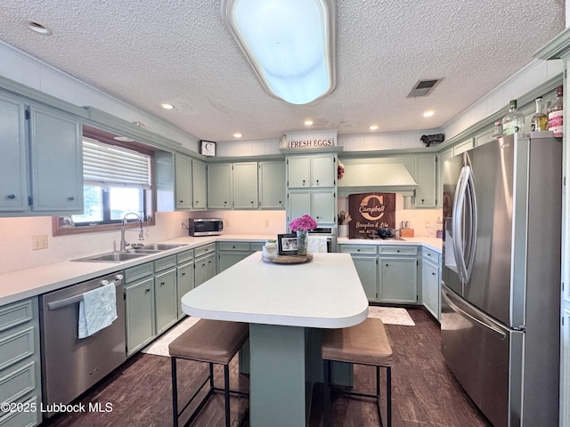914 W Lee St, Floydada, TX 79235 - kitchen with stainless steel appliances, a textured ceiling, dark wood finished floors, a breakfast bar area, and green cabinets