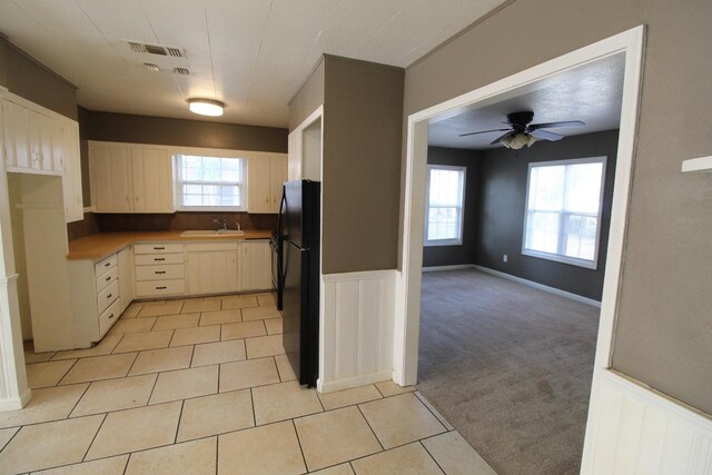 kitchen with plenty of natural light, black refrigerator, sink, and light colored carpet