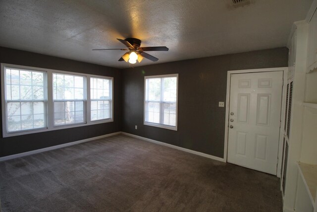 entrance foyer featuring ceiling fan, a textured ceiling, and dark colored carpet