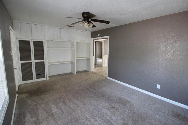 unfurnished bedroom with ceiling fan, light colored carpet, and a textured ceiling