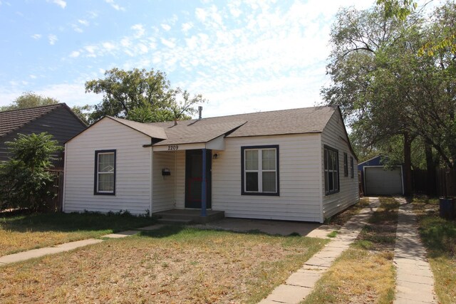 view of front of home with a garage, an outdoor structure, and a front yard