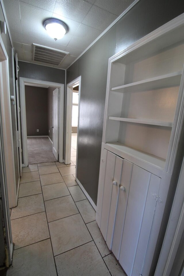 hallway with light tile patterned floors and crown molding