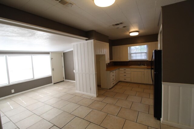 kitchen with light tile patterned flooring and black fridge