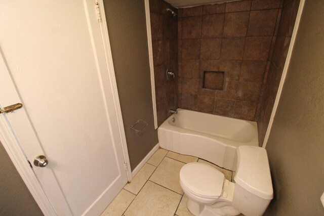 bathroom with toilet, tiled shower / bath combo, and tile patterned flooring