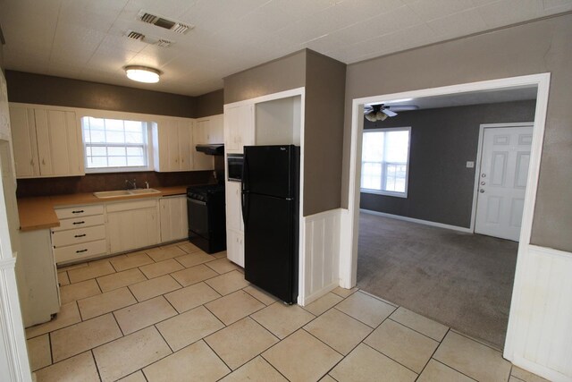 kitchen featuring sink, light colored carpet, ceiling fan, and black appliances