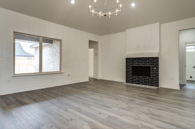 unfurnished living room with hardwood / wood-style flooring, a tiled fireplace, and an inviting chandelier