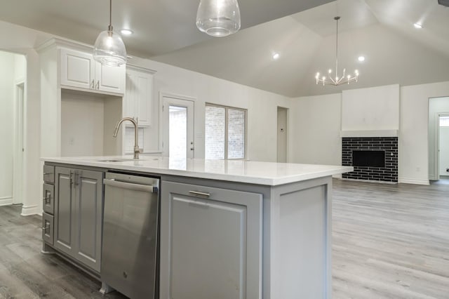 kitchen with pendant lighting, white cabinetry, a fireplace, and an island with sink