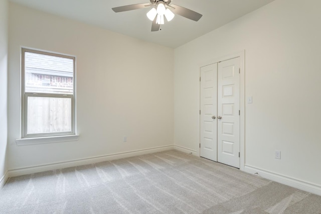 unfurnished bedroom featuring light carpet, a closet, and ceiling fan