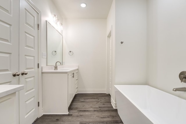 bathroom with vanity, a bath, and hardwood / wood-style flooring