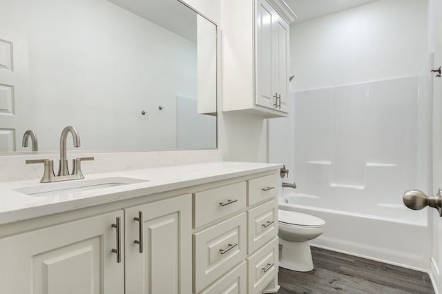 full bathroom with hardwood / wood-style flooring, vanity, washtub / shower combination, and toilet