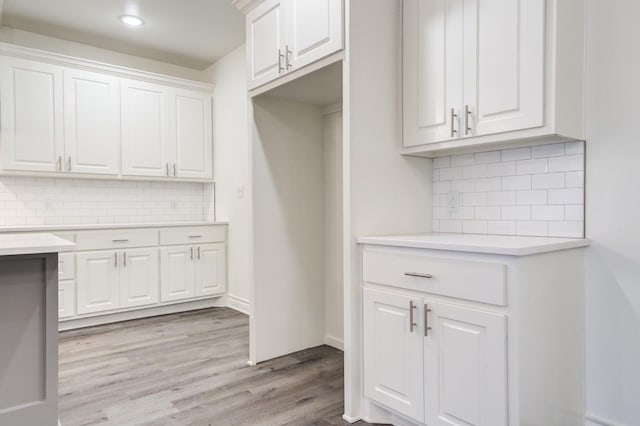 kitchen with tasteful backsplash, white cabinetry, and light wood-type flooring