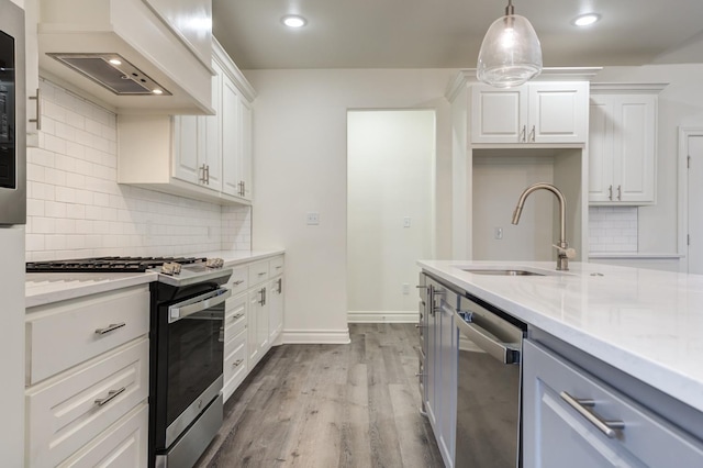 kitchen featuring sink, appliances with stainless steel finishes, hanging light fixtures, custom range hood, and white cabinets