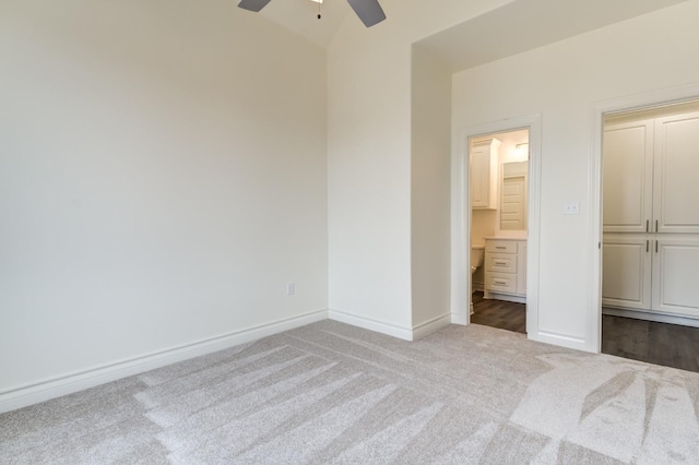 unfurnished bedroom featuring ceiling fan, lofted ceiling, carpet floors, and ensuite bath