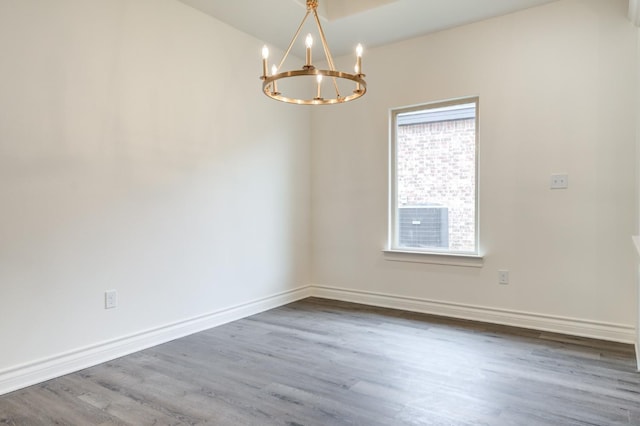 spare room with hardwood / wood-style floors and an inviting chandelier