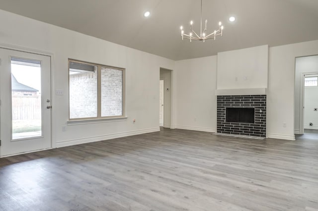 unfurnished living room with wood-type flooring, a tile fireplace, and a notable chandelier