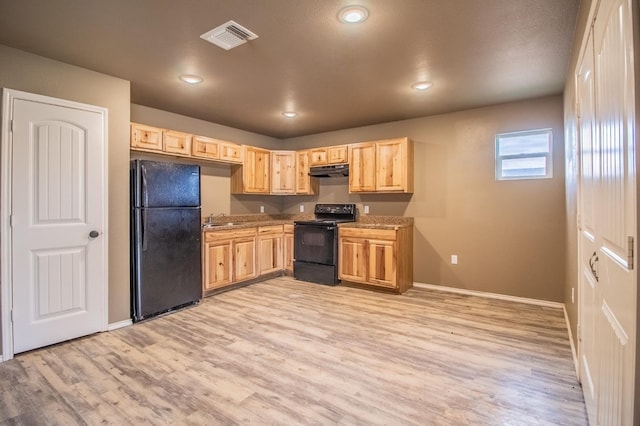 kitchen featuring black appliances, sink, light stone counters, light hardwood / wood-style floors, and light brown cabinets