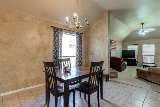 dining area with lofted ceiling, ceiling fan with notable chandelier, and light tile patterned floors