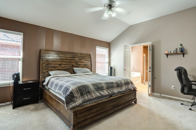 carpeted bedroom featuring ceiling fan, ensuite bath, vaulted ceiling, and multiple windows