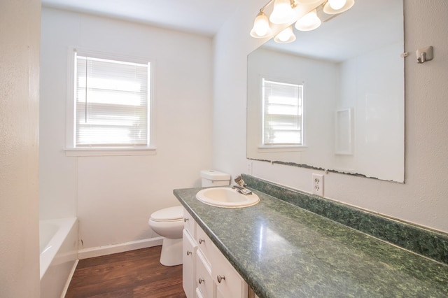 bathroom featuring wood-type flooring, a healthy amount of sunlight, vanity, and a bathtub