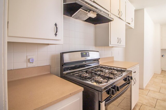 kitchen featuring tasteful backsplash, gas range oven, light tile patterned floors, and white cabinets