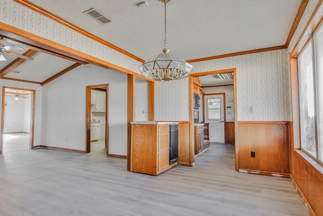 kitchen with ceiling fan with notable chandelier, stainless steel microwave, hanging light fixtures, a textured ceiling, and light hardwood / wood-style flooring