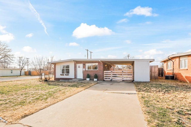 view of front facade featuring central AC, a carport, and a front yard