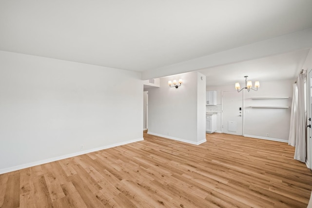 empty room with an inviting chandelier and light hardwood / wood-style flooring