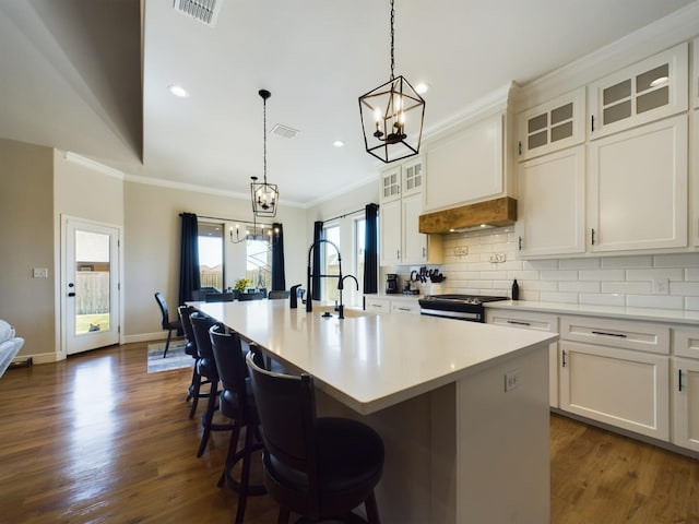 kitchen featuring gas stove, visible vents, crown molding, and decorative backsplash