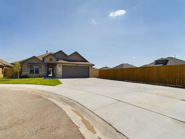 view of front of house with an attached garage, fence, stone siding, driveway, and a front lawn