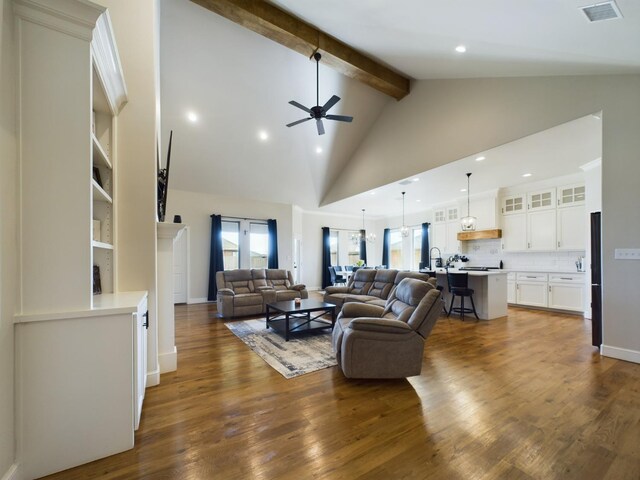 living room with visible vents, a ceiling fan, dark wood-style flooring, high vaulted ceiling, and beam ceiling