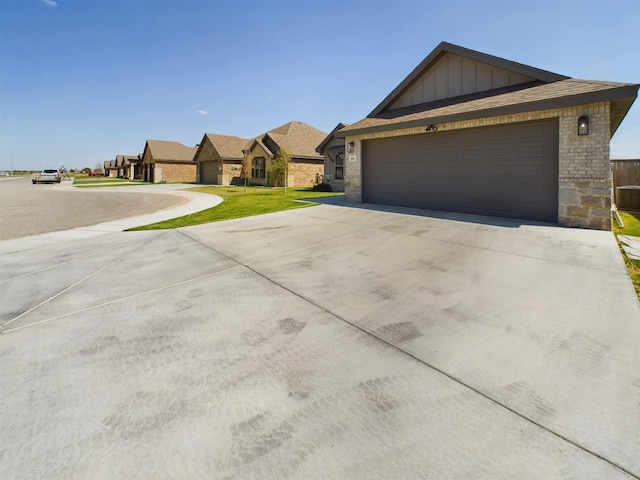 view of front facade featuring brick siding, an attached garage, board and batten siding, a front yard, and driveway