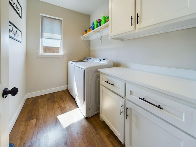 washroom featuring cabinet space, dark wood finished floors, baseboards, and separate washer and dryer