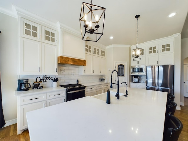 kitchen featuring a sink, appliances with stainless steel finishes, decorative backsplash, dark wood finished floors, and a center island with sink