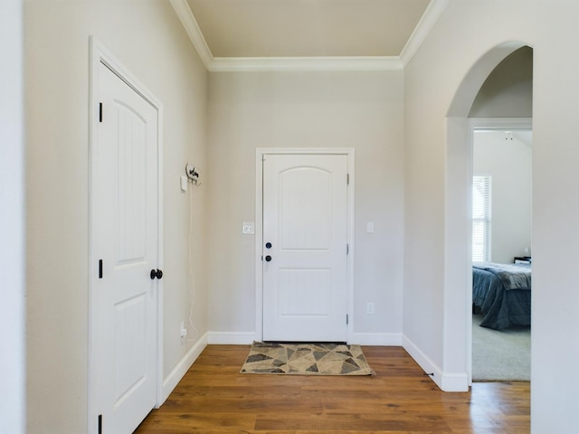 foyer with arched walkways, crown molding, and wood finished floors