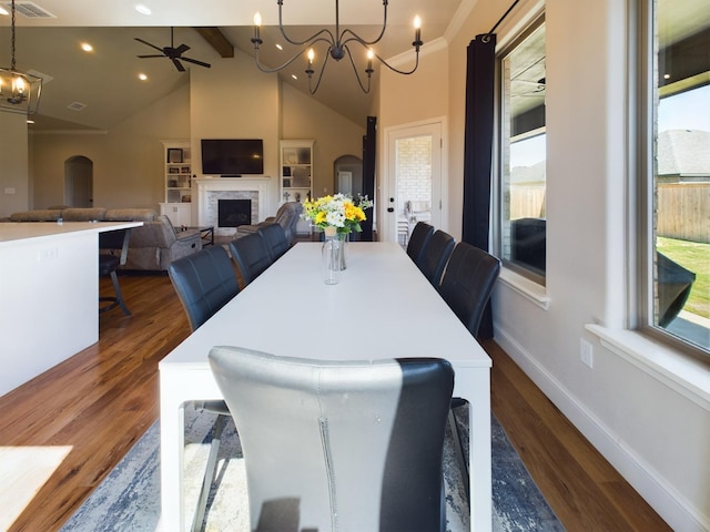 dining room with arched walkways, beamed ceiling, dark wood-style flooring, and a fireplace