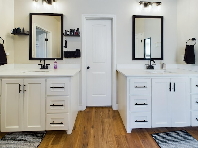 full bath featuring two vanities, a sink, and wood finished floors