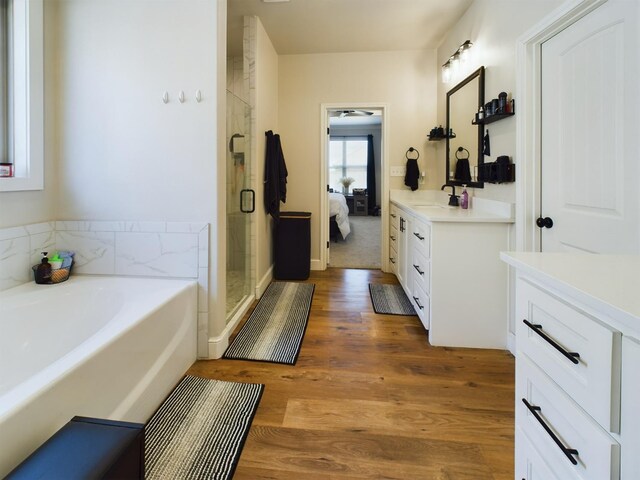 bathroom featuring a garden tub, connected bathroom, wood finished floors, vanity, and a stall shower