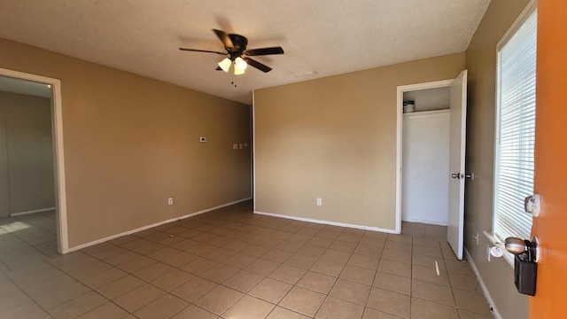 unfurnished bedroom featuring light tile patterned flooring, ceiling fan, a closet, and a textured ceiling