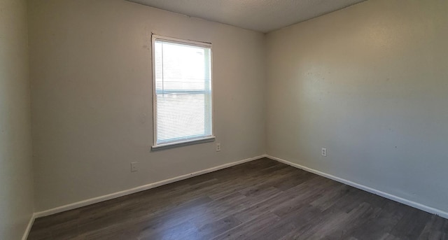 empty room featuring a textured ceiling and dark hardwood / wood-style flooring