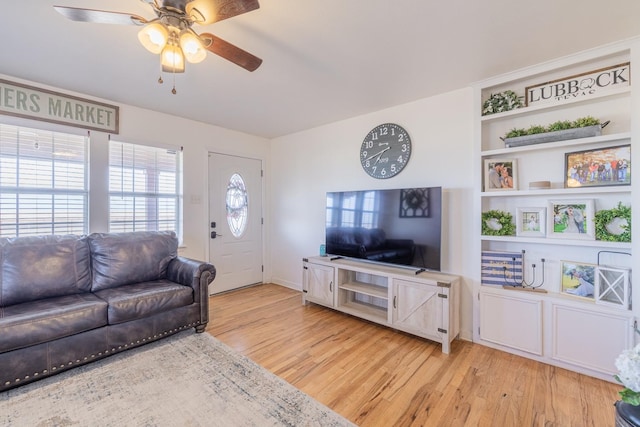 living room featuring built in shelves, ceiling fan, and light hardwood / wood-style flooring