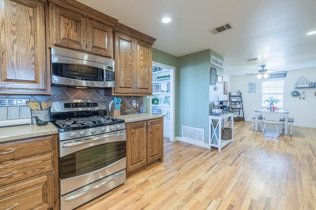 kitchen featuring ceiling fan, appliances with stainless steel finishes, light hardwood / wood-style floors, and decorative backsplash