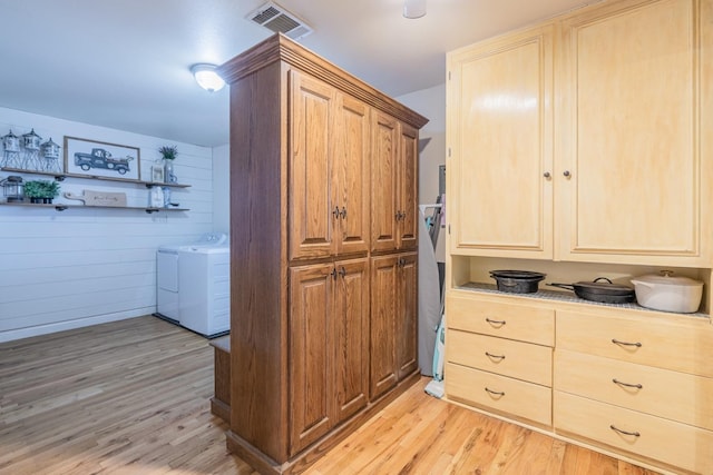 interior space featuring wooden walls, washer and clothes dryer, and light wood-type flooring