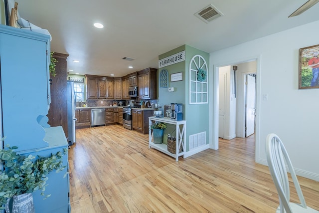 kitchen featuring tasteful backsplash, stainless steel appliances, and light wood-type flooring