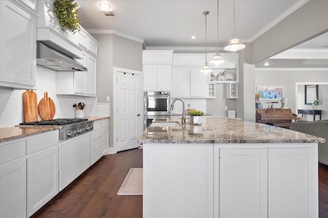 kitchen with pendant lighting, appliances with stainless steel finishes, white cabinets, and a center island with sink