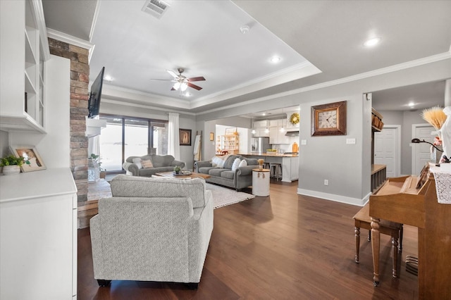 living room featuring ornamental molding, ceiling fan, dark hardwood / wood-style flooring, and a tray ceiling