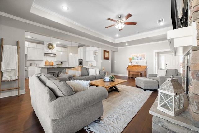 living room featuring crown molding, dark hardwood / wood-style floors, ceiling fan, and a tray ceiling