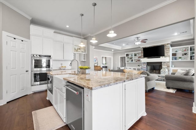 kitchen featuring stainless steel appliances, an island with sink, pendant lighting, and white cabinets