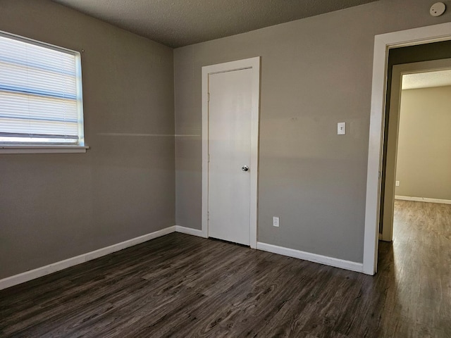 unfurnished bedroom featuring dark wood-type flooring and a textured ceiling