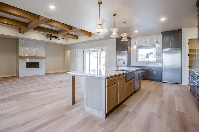 kitchen with pendant lighting, a kitchen island with sink, stainless steel appliances, coffered ceiling, and light hardwood / wood-style floors