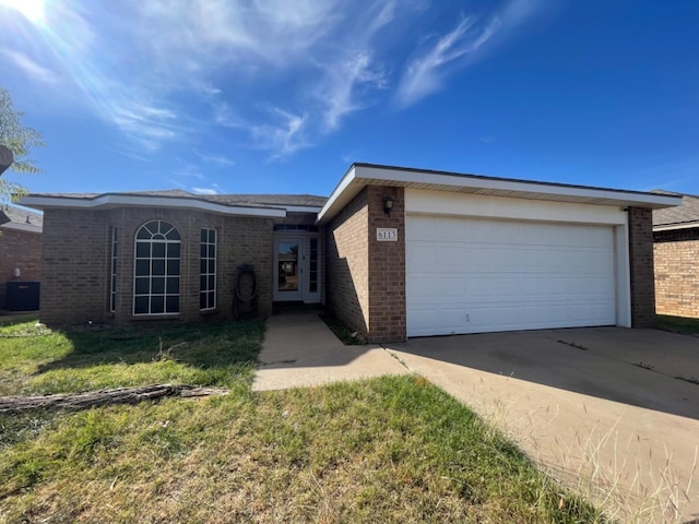 ranch-style house with central AC unit, a garage, and a front yard